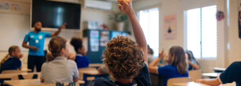 Boy raising his hand in class to go to the bathroom