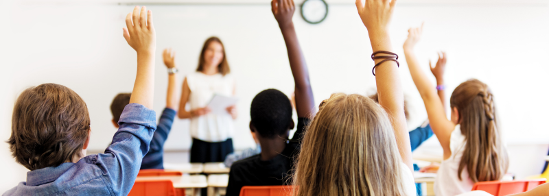 Children raising their hand while they are in class at school