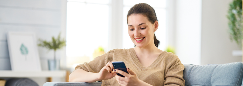 Woman sitting on the couch using her phone to make a call