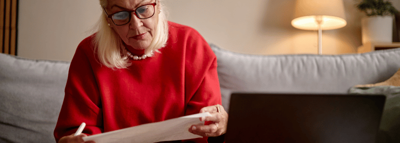Older woman reviewing documents while sitting on her couch