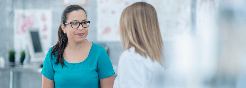 Woman speaking to healthcare provider in exam room