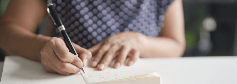 Woman writing in notebook at her desk